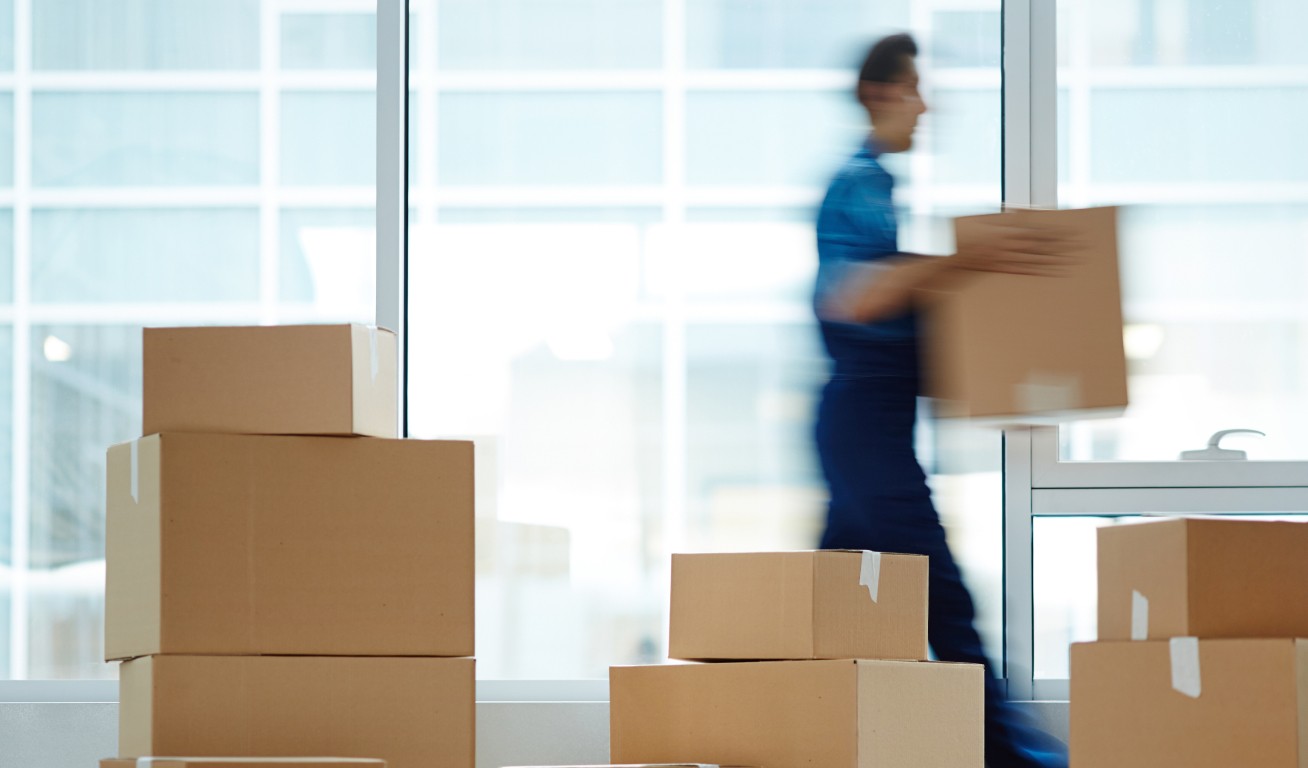 Busy Mover - Active Relocation Blurred mover carrying boxes in front of a glass building