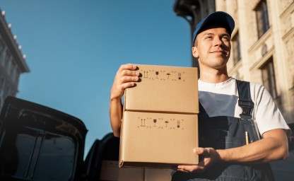 Parcel Delivery - Courier with Package Delivery man holding a cardboard box on a sunny day